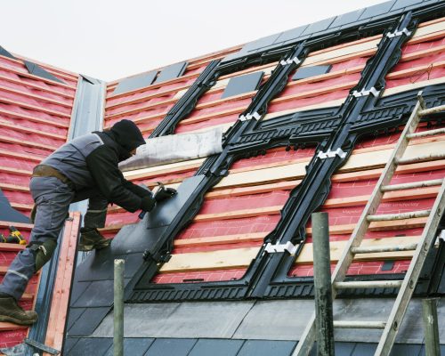 A roofer replacing the tiles on a house roof.